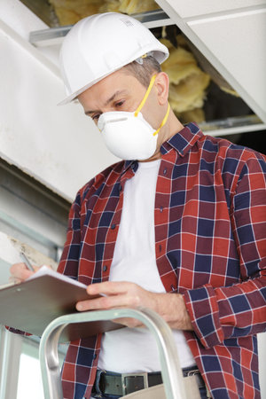 worker with mask holding black clipboard and thinking