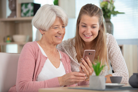 daughter helping senior mum to use phone