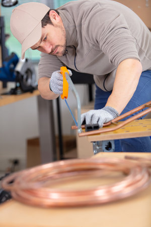 plumber cutting a copper pipe with a pipe cutterの写真素材