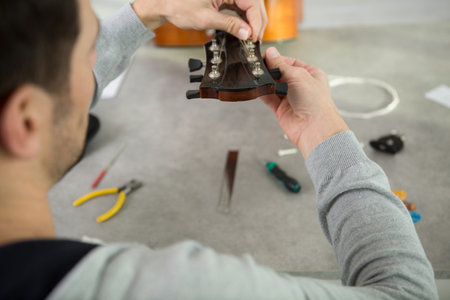 pair of male hands fixing a guitarの写真素材