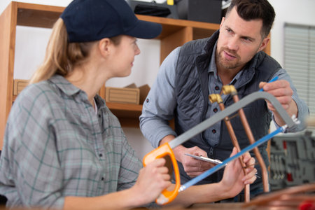 tradeswoman cutting copper pipe with hacksawの写真素材