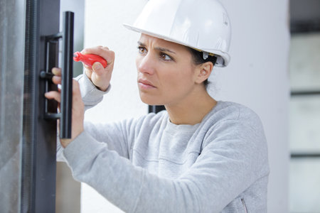 young carpenter woman installing screwed doorの写真素材