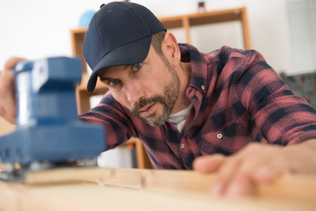 man sanding wood with electric sander polisherの写真素材