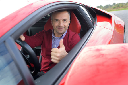 man confident driving a red car