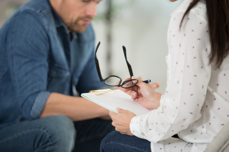 therapist listening to patient and holding her eyeglassesの写真素材