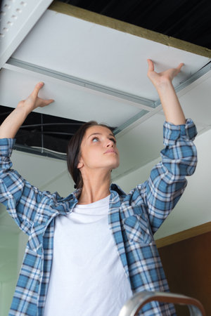 a female builder repairing ceilingの写真素材