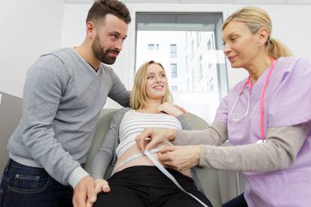 gynecologist measuring bump during check-upの写真素材