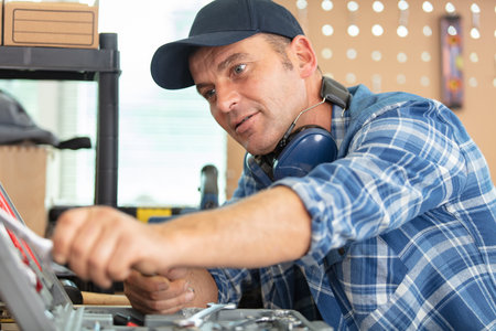 man in workshop reaches for a toolの写真素材