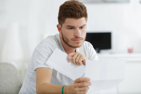 shocked man holding some documents on sofa livingroomの写真素材