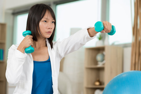 serious young woman holding dumbells indoorの写真素材