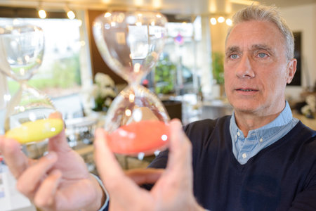 businessman holding two sand-clocks in the officeの写真素材
