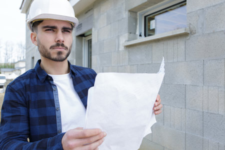 man in hardhat looking at plansの写真素材