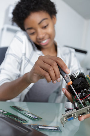 woman on the phone holds a screwdriver to repair laptopの写真素材