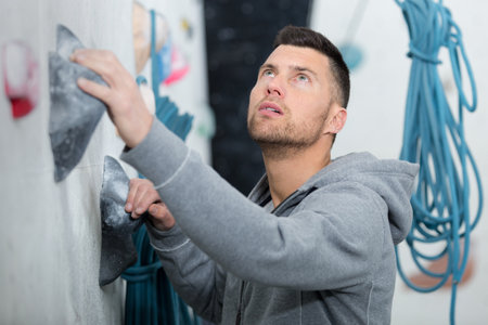 man reaching for a grip while climbing indoorsの写真素材