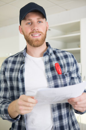 young engineer working on construction site and holding a blueprintの写真素材