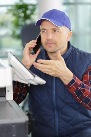 handyman fixing printer while talking on the phone