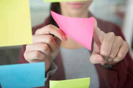 business hand picking sticky notes on glass wall