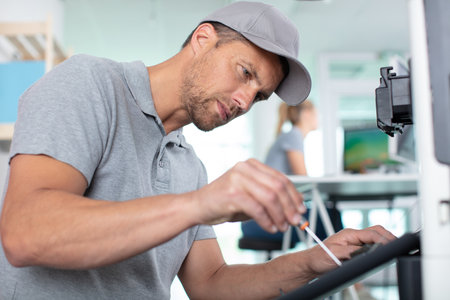 young male technician repairing digital photocopier machineの写真素材