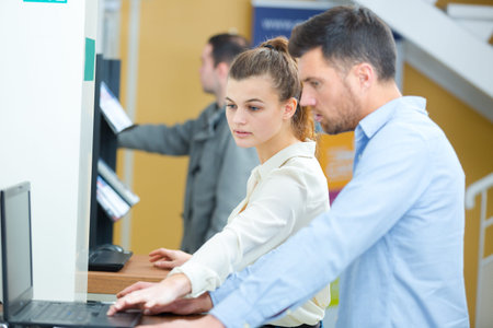 portrait of young woman and man looking at laptop