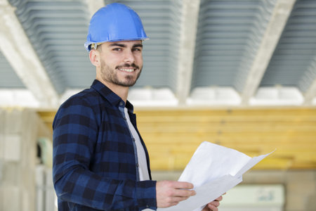 portrait of builder on site with plans