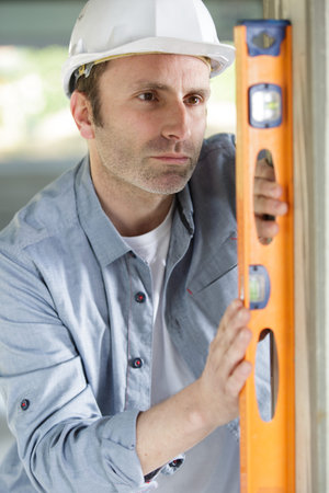 worker using spirit level on a wooden door frame