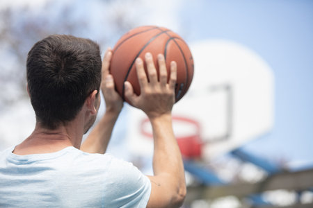 adult male holding basketball and aiming towards netの写真素材