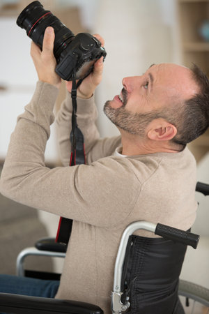 man in wheelchair training to become photographerの写真素材