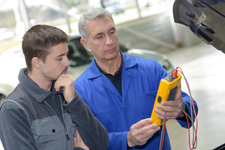 student with instructor repairing a car during apprenticeshipの写真素材