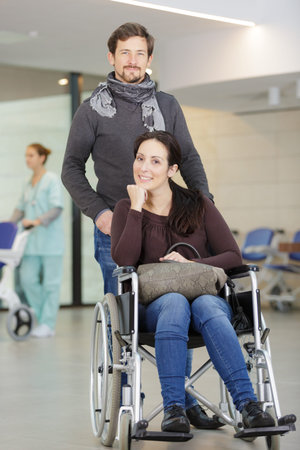 man helping woman in wheelchair in hospital