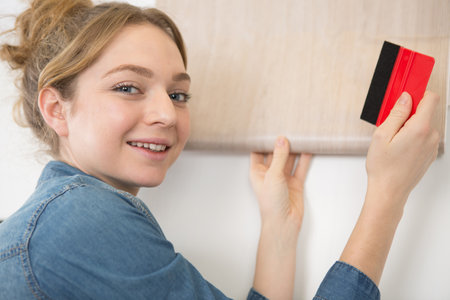 happy woman is removing wall paperの写真素材