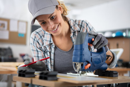 female carpenter sawing in workshopの写真素材