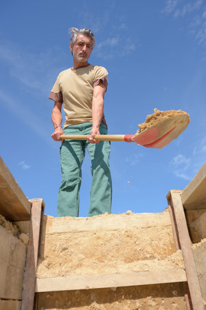 male cemetery worker digging a graveの写真素材