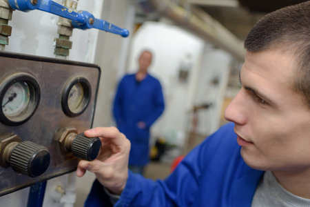 teenage apprentice operating machinery in factoryの写真素材