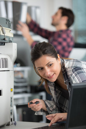 young woman is fixing a printer