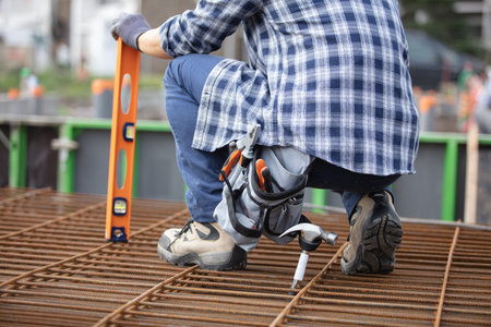 tradesman crouching on stack of reinforcement bars