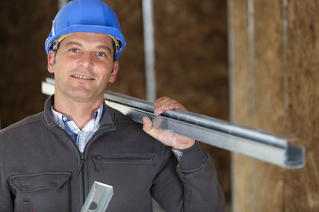 construction worker wearing harhat and holding metal barsの写真素材