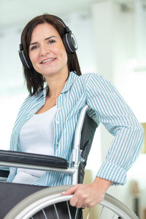 positive young woman in wheelchair wearing headphones