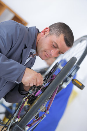 man repairing a bicycle with a wrenchの写真素材