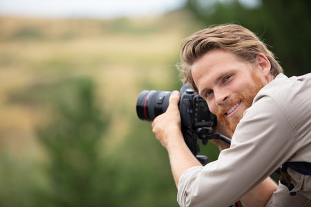 man photographer and traveler holding camera taking photosの写真素材