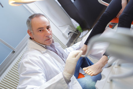 woman receives foot examination from gloved podiatristの写真素材