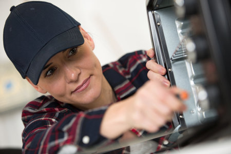 female electrician fixing oven unitの写真素材