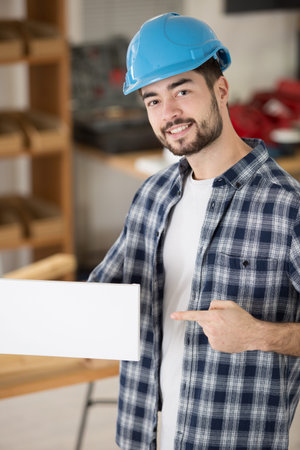 young builder man pointing at a white blank banner