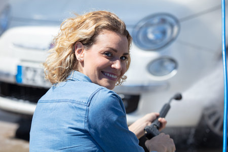 young woman driver cleaning her car at carwashの写真素材