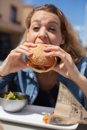 woman eating a large chicken burgerの写真素材