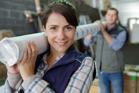 man and woman carrying a roll in a factoryの写真素材