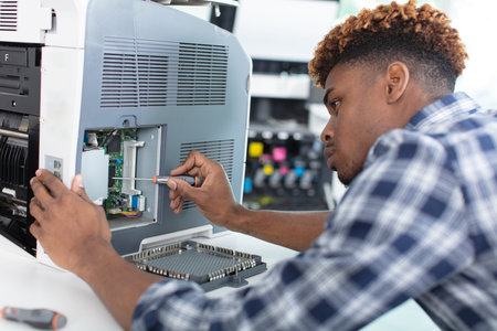 he holds a screwdriver for fixing printer