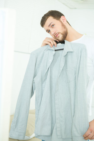 attractive and strong young man choosing shirtの写真素材