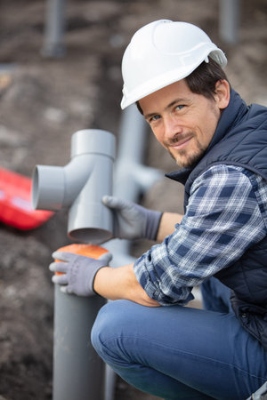 plumber assembling pvc sewage pipes in house foundation