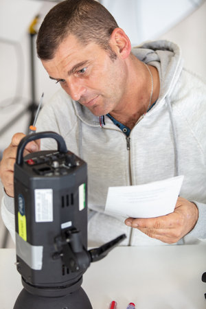 man works on lighting for photography studio
