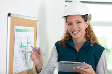 female surveyor with clipboard talking to builder on construction siteの写真素材